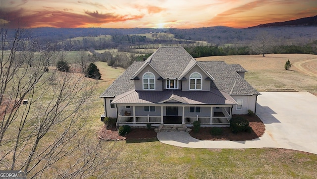 view of front of property with a forest view, covered porch, a mountain view, and a lawn