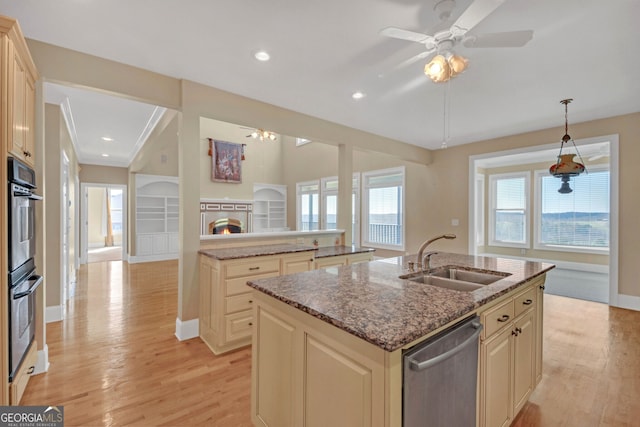 kitchen featuring a kitchen island with sink, stainless steel appliances, a sink, a lit fireplace, and light wood finished floors