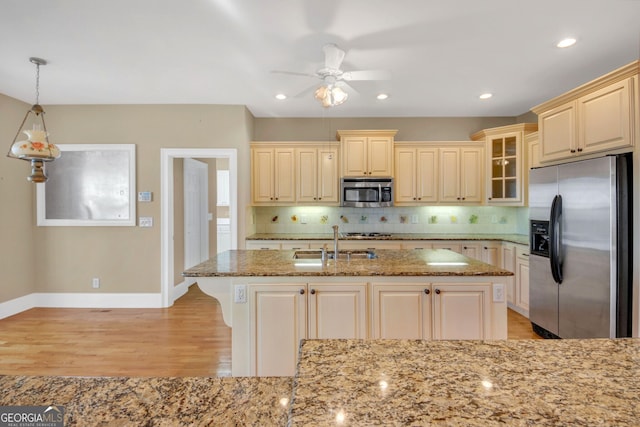 kitchen featuring light stone countertops, light wood-style floors, tasteful backsplash, and appliances with stainless steel finishes