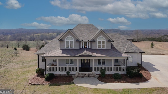 view of front of property with driveway, metal roof, roof with shingles, covered porch, and a standing seam roof