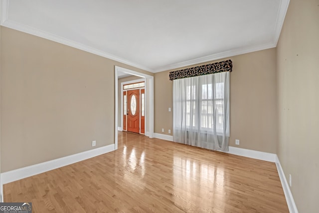 spare room featuring crown molding, baseboards, and wood finished floors