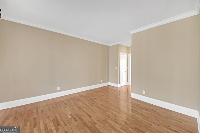 unfurnished room with ornamental molding, light wood finished floors, and baseboards