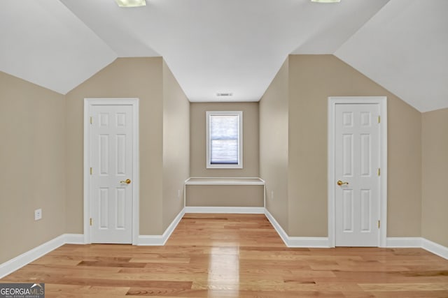 bonus room featuring vaulted ceiling, light wood-style flooring, and baseboards