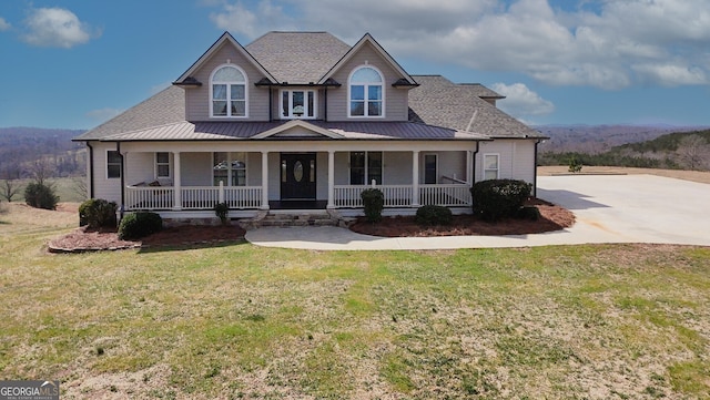 view of front facade with a standing seam roof, metal roof, a porch, and a front lawn