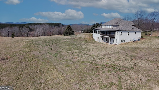 exterior space with a sunroom, a mountain view, and a yard