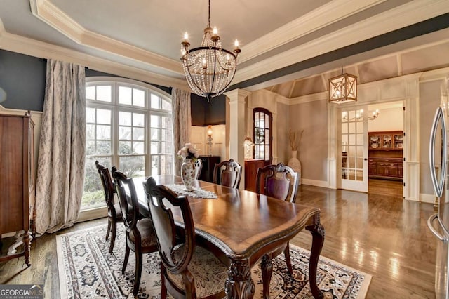 dining area with crown molding, a tray ceiling, decorative columns, and an inviting chandelier