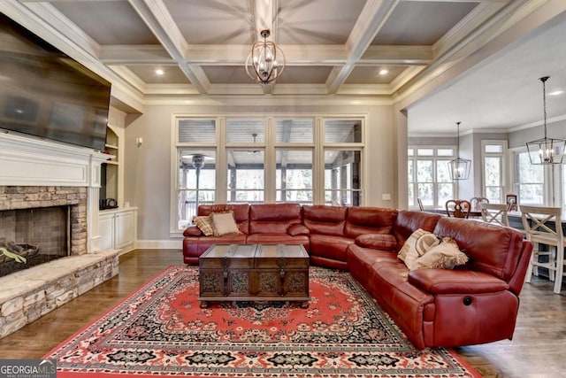 living room with beamed ceiling, a fireplace, wood finished floors, and a notable chandelier