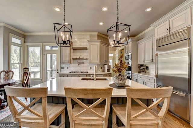 kitchen with crown molding, a healthy amount of sunlight, a sink, and built in appliances