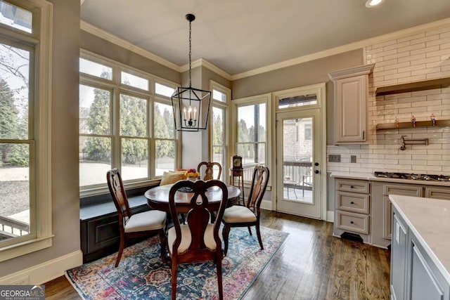 dining room with ornamental molding, dark wood-type flooring, a notable chandelier, and baseboards