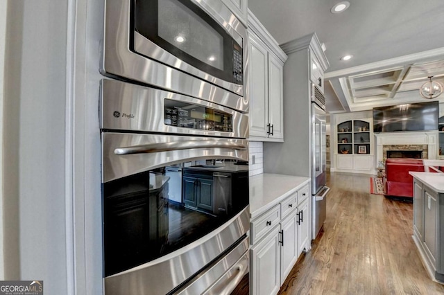 kitchen with stainless steel appliances, light countertops, open floor plan, wood finished floors, and coffered ceiling