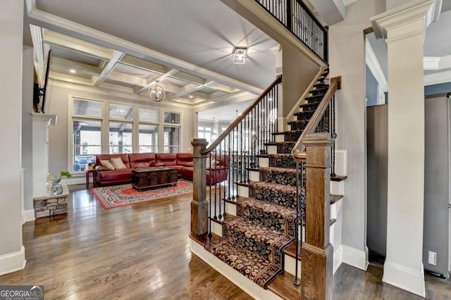 staircase featuring coffered ceiling, wood finished floors, a wealth of natural light, and ornate columns