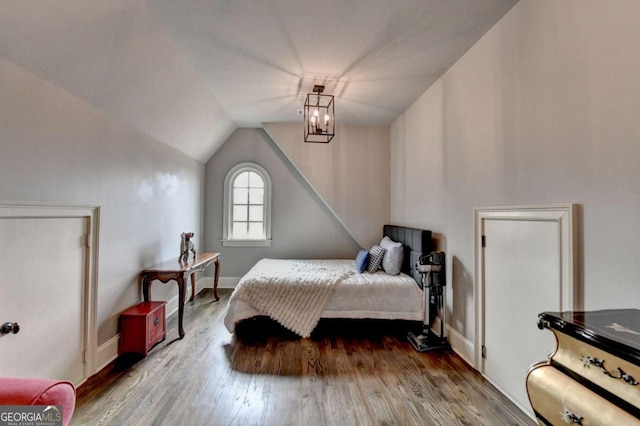 bedroom with lofted ceiling, a notable chandelier, baseboards, and wood finished floors