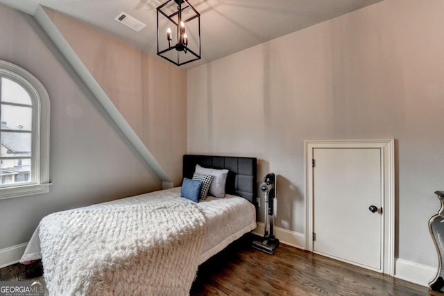 bedroom featuring a chandelier, visible vents, baseboards, and wood finished floors