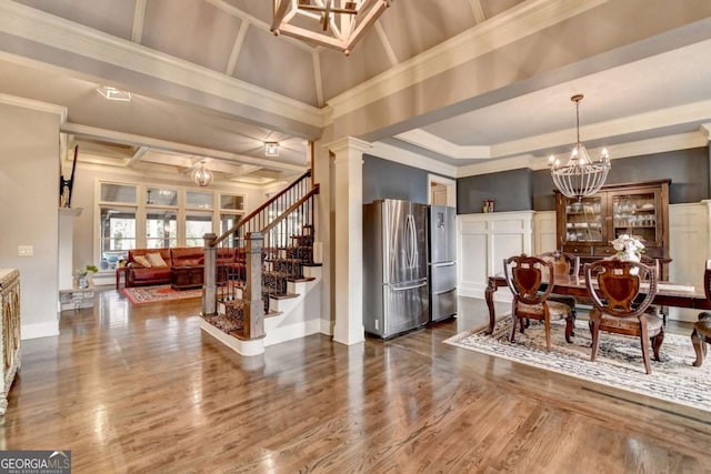 dining area featuring a decorative wall, stairway, wood finished floors, and an inviting chandelier