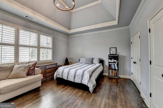 bedroom featuring wood finished floors, visible vents, baseboards, a tray ceiling, and crown molding