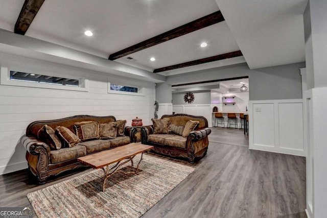 living room featuring wainscoting, beamed ceiling, and wood finished floors