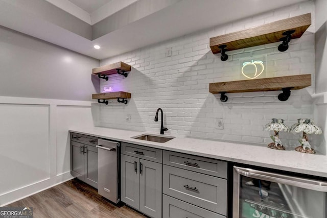 bar featuring wine cooler, dark wood-style flooring, decorative backsplash, wainscoting, and a sink