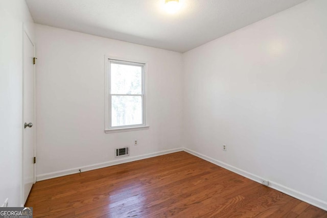 spare room with visible vents, baseboards, and wood finished floors