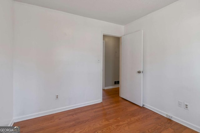 unfurnished room featuring visible vents, baseboards, and wood finished floors