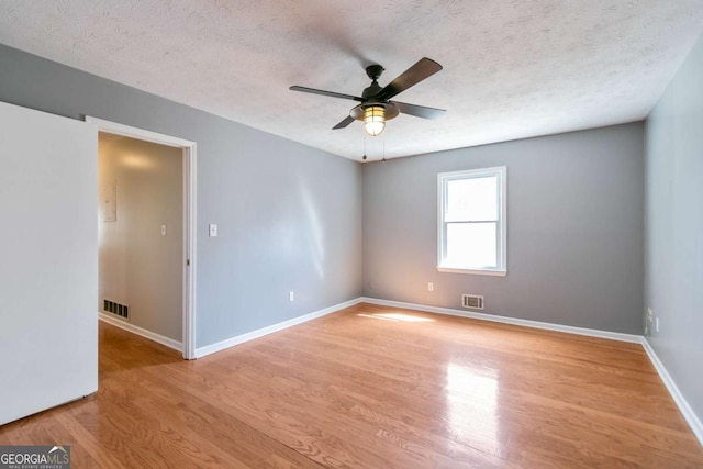 spare room featuring ceiling fan, baseboards, visible vents, and light wood-style floors