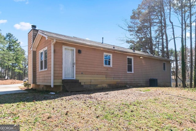 exterior space featuring entry steps, central AC, and a chimney