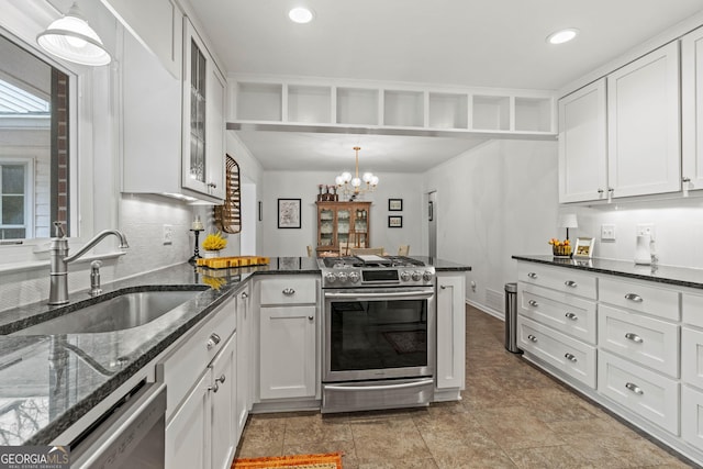 kitchen featuring stainless steel appliances, a sink, white cabinets, dark stone counters, and glass insert cabinets