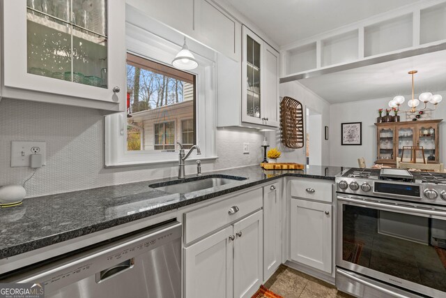 kitchen with appliances with stainless steel finishes, a sink, white cabinets, and decorative backsplash