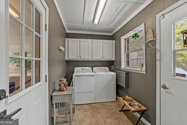 laundry room with cabinet space, separate washer and dryer, and wood walls