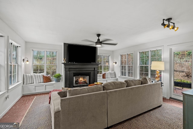 living area featuring ceiling fan, a fireplace, and baseboards