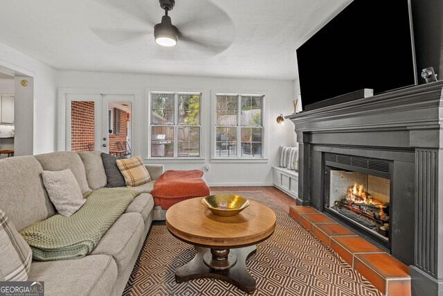 living room with a ceiling fan, a warm lit fireplace, and baseboards