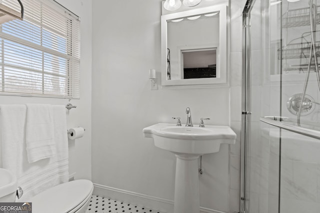 bathroom featuring a stall shower, toilet, and baseboards