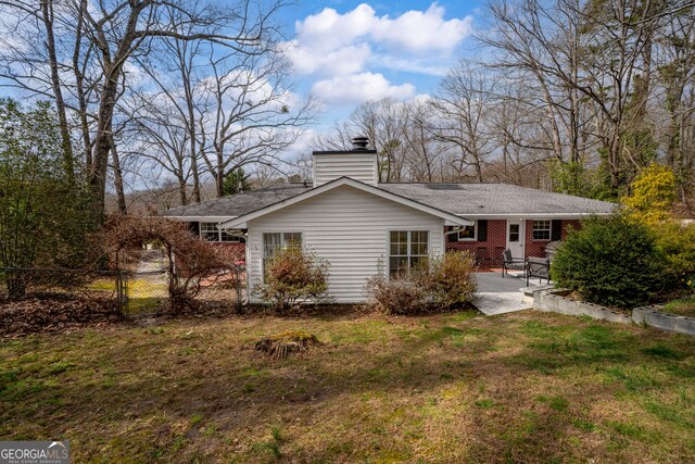 rear view of property with brick siding, a yard, a gate, a patio area, and fence