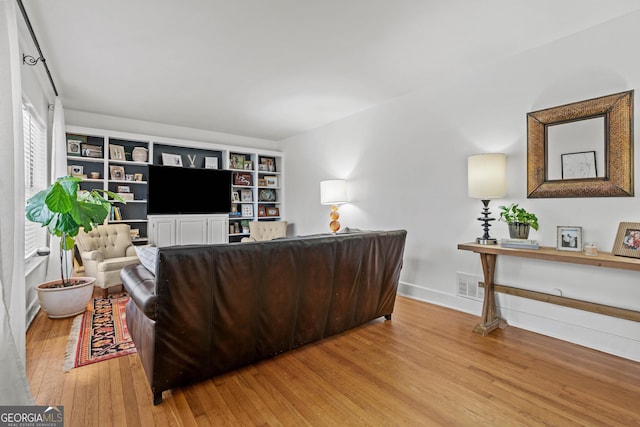 living area with baseboards, visible vents, and hardwood / wood-style floors