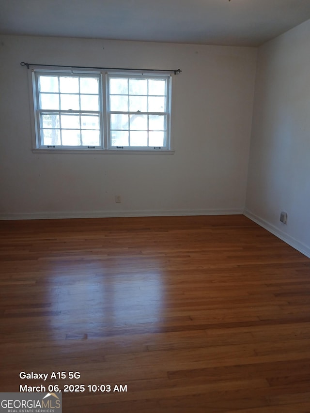 unfurnished room with a wealth of natural light, baseboards, and wood finished floors