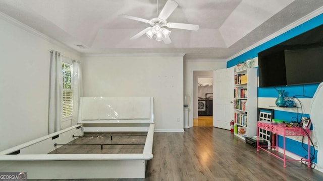 misc room with a ceiling fan, a tray ceiling, crown molding, and wood finished floors