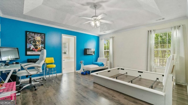 bedroom with multiple windows, ornamental molding, a raised ceiling, and wood finished floors