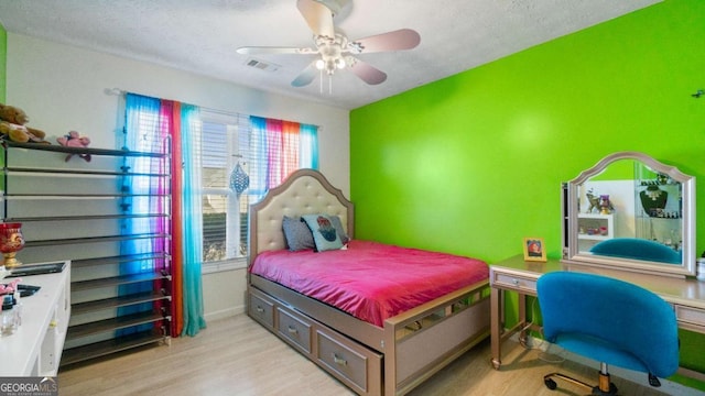 bedroom featuring visible vents, ceiling fan, baseboards, and wood finished floors