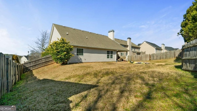 rear view of house featuring a fenced backyard and a yard