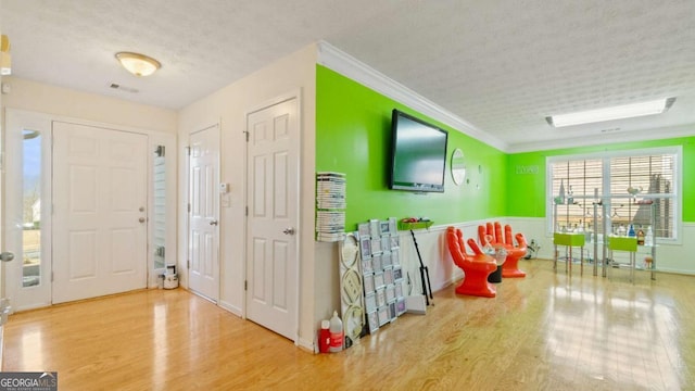 foyer with visible vents, crown molding, a textured ceiling, and wood finished floors