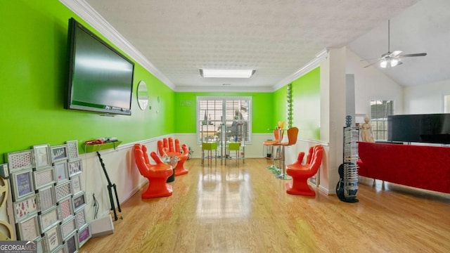 playroom featuring ceiling fan, a textured ceiling, ornamental molding, and wood finished floors