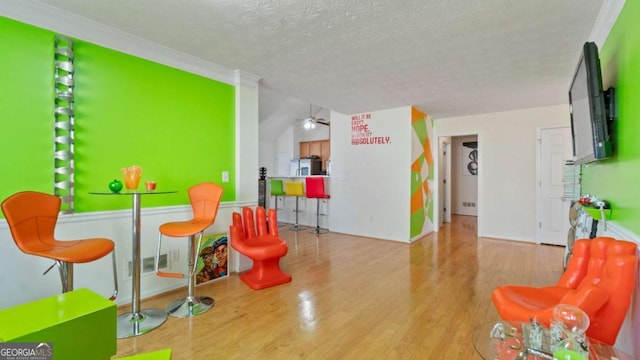 recreation room with a textured ceiling, ceiling fan, and wood finished floors