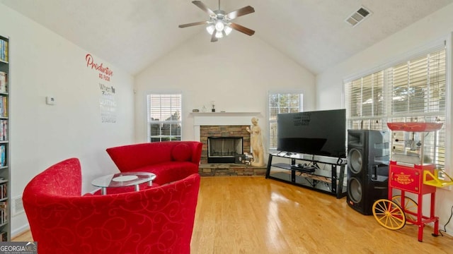 living room featuring a fireplace, visible vents, a ceiling fan, wood finished floors, and high vaulted ceiling