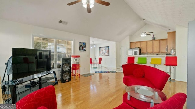 living room with high vaulted ceiling, a ceiling fan, visible vents, and wood finished floors