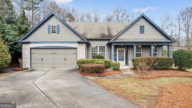 view of front of home featuring a garage, stone siding, roof with shingles, and driveway