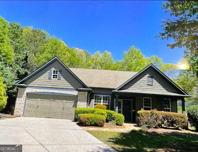 view of front of home with driveway, an attached garage, and stone siding