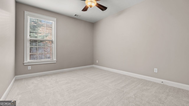 carpeted spare room featuring a ceiling fan, visible vents, and baseboards