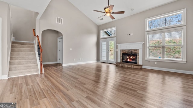 unfurnished living room featuring arched walkways, visible vents, a wealth of natural light, and ceiling fan