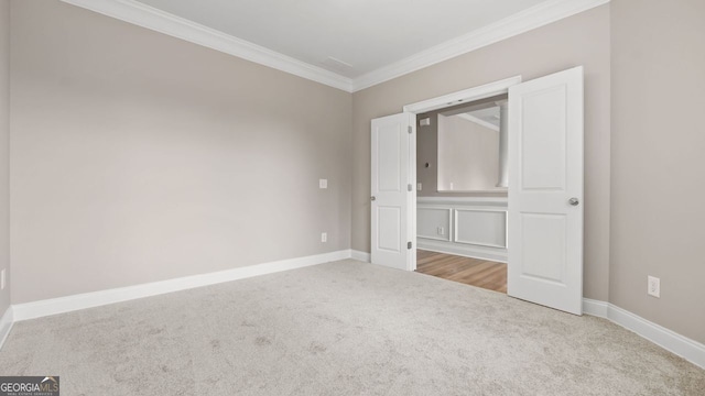empty room featuring baseboards, crown molding, and carpet flooring