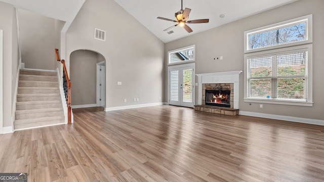 unfurnished living room featuring visible vents, ceiling fan, plenty of natural light, arched walkways, and high vaulted ceiling