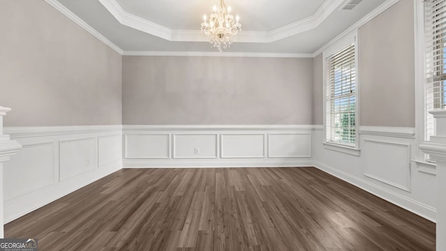 unfurnished dining area with wainscoting, a notable chandelier, dark wood-style flooring, and a tray ceiling